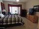 Large bedroom features a bed, sitting chair, black dresser, and a TV on a dresser at 15104 W Pinehurst W Ln, Surprise, AZ 85374