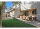Fenced backyard with artificial grass, string lights, outdoor seating, and dining area at 18841 E Pelican Ct, Queen Creek, AZ 85142