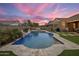 Backyard pool with a waterfall feature, surrounding patio, and lush landscaping against a sunset backdrop at 20040 E Kestrel St, Queen Creek, AZ 85142