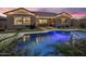 Backyard at dusk featuring a sparkling in-ground pool with patio and lush tropical landscaping at 20040 E Kestrel St, Queen Creek, AZ 85142