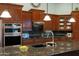 Close up of a kitchen island with granite countertops, dark wood cabinets, and stainless steel appliances at 20331 N Fletcher Way, Peoria, AZ 85382