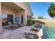 Covered patio with stylish seating overlooks a backyard with a pool and lush landscaping, perfect for relaxation at 20331 N Fletcher Way, Peoria, AZ 85382