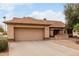 A tan home with a two-car garage featuring mature desert landscaping at 20408 N Tanglewood Dr, Sun City West, AZ 85375