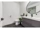 Sleek bathroom featuring a modern gray vanity, round mirror, and stylish fixtures at 2202 E Lincoln Dr, Phoenix, AZ 85016