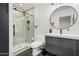 This modern bathroom features a glass enclosed shower, a round mirror, contemporary light fixture and dark flooring at 2202 E Lincoln Dr, Phoenix, AZ 85016