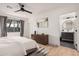 This bedroom has light wood floors, a dark wood dresser, a ceiling fan, large mirror and ensuite bathroom at 2202 E Lincoln Dr, Phoenix, AZ 85016