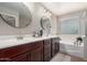 Bathroom featuring a double sink vanity, framed mirrors, and a separate soaking tub at 3192 N Park St, Buckeye, AZ 85396