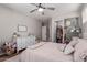 Charming bedroom featuring soft pink bedding, a ceiling fan, and a unique closet door with vintage-inspired decor at 3192 N Park St, Buckeye, AZ 85396