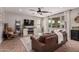 Inviting living room with a ceiling fan, a cozy leather sofa, a fireplace, and lots of natural light at 3192 N Park St, Buckeye, AZ 85396