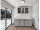 Bright kitchenette features gray cabinets with glass fronts and quartz countertops with a view to the backyard at 4237 E Clovis Ave, Mesa, AZ 85206