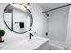 Stylish bathroom with a round mirror, modern vanity, and a shower-tub combination with marble tile at 7818 E Cactus Wren Rd, Scottsdale, AZ 85250