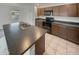 Kitchen featuring an island, stainless steel appliances, dark wood cabinetry, and tile floors at 8886 S 256Th Dr, Buckeye, AZ 85326