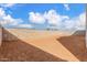 Spacious dirt backyard with cinderblock fence under a sunny, partly cloudy sky at 10302 E Utah Ave, Mesa, AZ 85212