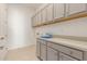 Spacious laundry room with ample gray cabinetry, a pristine white countertop, and tile flooring at 10302 E Utah Ave, Mesa, AZ 85212