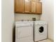 Bright laundry room with cabinetry above the washer and dryer providing functional storage and organization at 10812 N 117Th Pl, Scottsdale, AZ 85259