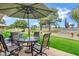 Back patio with an umbrella, chairs, and a table overlooking the lush green golf course at 12534 W Ashwood Dr, Sun City West, AZ 85375