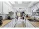 Galley kitchen featuring white cabinets, modern appliances, light wood floors and an open view of the dining and living area at 12534 W Ashwood Dr, Sun City West, AZ 85375