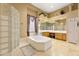 Serene main bathroom with a soaking tub, tiled floor, and glass block wall at 12706 E Desert Cove Ave, Scottsdale, AZ 85259