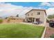 Large backyard featuring lush artificial grass, a brick-paved patio, and multiple seating areas at 13153 W Clarendon Ave, Litchfield Park, AZ 85340