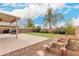 Landscaped backyard with grass, patio with brick pavers and a fire pit area including planting beds with rocks at 13153 W Clarendon Ave, Litchfield Park, AZ 85340