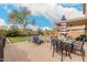 Brick-paved patio featuring an outdoor dining table with umbrella and seating next to a manicured lawn with desert plants at 13153 W Clarendon Ave, Litchfield Park, AZ 85340