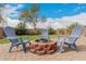 Firepit area on a brick-paved patio featuring three Adirondack chairs and a view of the manicured lawn at 13153 W Clarendon Ave, Litchfield Park, AZ 85340