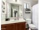 Well-lit bathroom with a single sink vanity, toilet and decorative shelving on the walls at 13153 W Clarendon Ave, Litchfield Park, AZ 85340