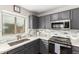 Well-lit kitchen featuring gray cabinets, stainless steel appliances, and stylish tile backsplash at 13153 W Clarendon Ave, Litchfield Park, AZ 85340