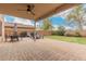 Covered patio features a ceiling fan, brick pavers, a dining table, grill, and outdoor seating area overlooking the green lawn at 13153 W Clarendon Ave, Litchfield Park, AZ 85340