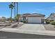 Charming desert home boasts a two-car garage, a tile roof, manicured landscaping, and multiple palm trees at 15501 W Las Verdes Way, Surprise, AZ 85374