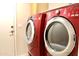 Close-up of the modern, red washer and dryer set with a white door and light switch in the background at 16243 N 27Th St, Phoenix, AZ 85032