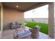 This covered back patio features wicker furniture, a coffee table, and artificial turf at 17162 W Corrine Dr, Surprise, AZ 85388