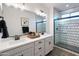 Bathroom with double sinks, modern light fixture, and walk-in shower with stylish tile at 17162 W Corrine Dr, Surprise, AZ 85388