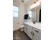 Bathroom with white vanity, a framed mirror, and a toilet next to a window at 17162 W Corrine Dr, Surprise, AZ 85388