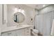 Well-lit bathroom featuring a shower with curtain, a vanity with a sink, and a round mirror at 17505 N 96Th Way, Scottsdale, AZ 85255