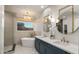 Bright bathroom featuring a soaking tub, frameless shower, a dual sink vanity with modern fixtures, and stylish lighting at 17505 N 96Th Way, Scottsdale, AZ 85255