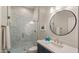 Modern bathroom featuring a glass shower, a round mirror, and a sleek vanity with a white countertop at 17505 N 96Th Way, Scottsdale, AZ 85255