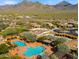 Panoramic view of a community pool complex featuring multiple pools, shaded lounge areas, and beautiful desert landscape and mountain backdrop at 17505 N 96Th Way, Scottsdale, AZ 85255