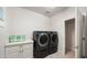 Modern laundry room with gray front load washer and dryer, quartz countertop, and painted cabinets at 17505 N 96Th Way, Scottsdale, AZ 85255