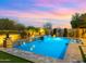 Inviting pool with water feature, baja shelf, and travertine tile surrounded by lush landscaping at 17505 N 96Th Way, Scottsdale, AZ 85255