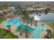 Stunning aerial view of a resort-style pool area surrounded by palm trees and a lake in a residential community at 20745 N Verbena Ln, Maricopa, AZ 85138