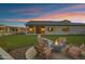 Home's outdoor space featuring a cozy seating area with lush green grass and an inviting fire pit at 20745 N Verbena Ln, Maricopa, AZ 85138