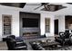 Modern living room with fireplace, brick accent wall, and black leather seating at 20745 N Verbena Ln, Maricopa, AZ 85138