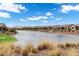 Water view of desert community with many homes on a bright, sunny day with fluffy clouds in the sky at 20745 N Verbena Ln, Maricopa, AZ 85138