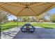 A covered picnic pavilion featuring a green picnic table with attached seating is surrounded by greenery and trees at 2501 E Los Alamos St, Gilbert, AZ 85295