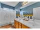 Bathroom featuring dual sinks, wood cabinets, decorative wall art, and shower with stylish curtains at 2688 S Racine Ct, Gilbert, AZ 85295