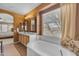 Bathroom featuring a double sink vanity, large tub with a window, and an arched doorway to a bedroom at 2688 S Racine Ct, Gilbert, AZ 85295