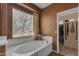 Bright bathroom featuring a large tub with a window and curtain, and a glimpse of the walk-in closet at 2688 S Racine Ct, Gilbert, AZ 85295