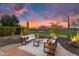 Cozy backyard featuring comfortable lounge seating, desert landscaping, and a picturesque golf course view at sunset at 28516 N 128Th Dr, Peoria, AZ 85383