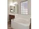 Bright bathroom featuring a soaking tub with a privacy window, vanity with mirror and tile flooring at 3223 W Rapalo Rd, Phoenix, AZ 85086